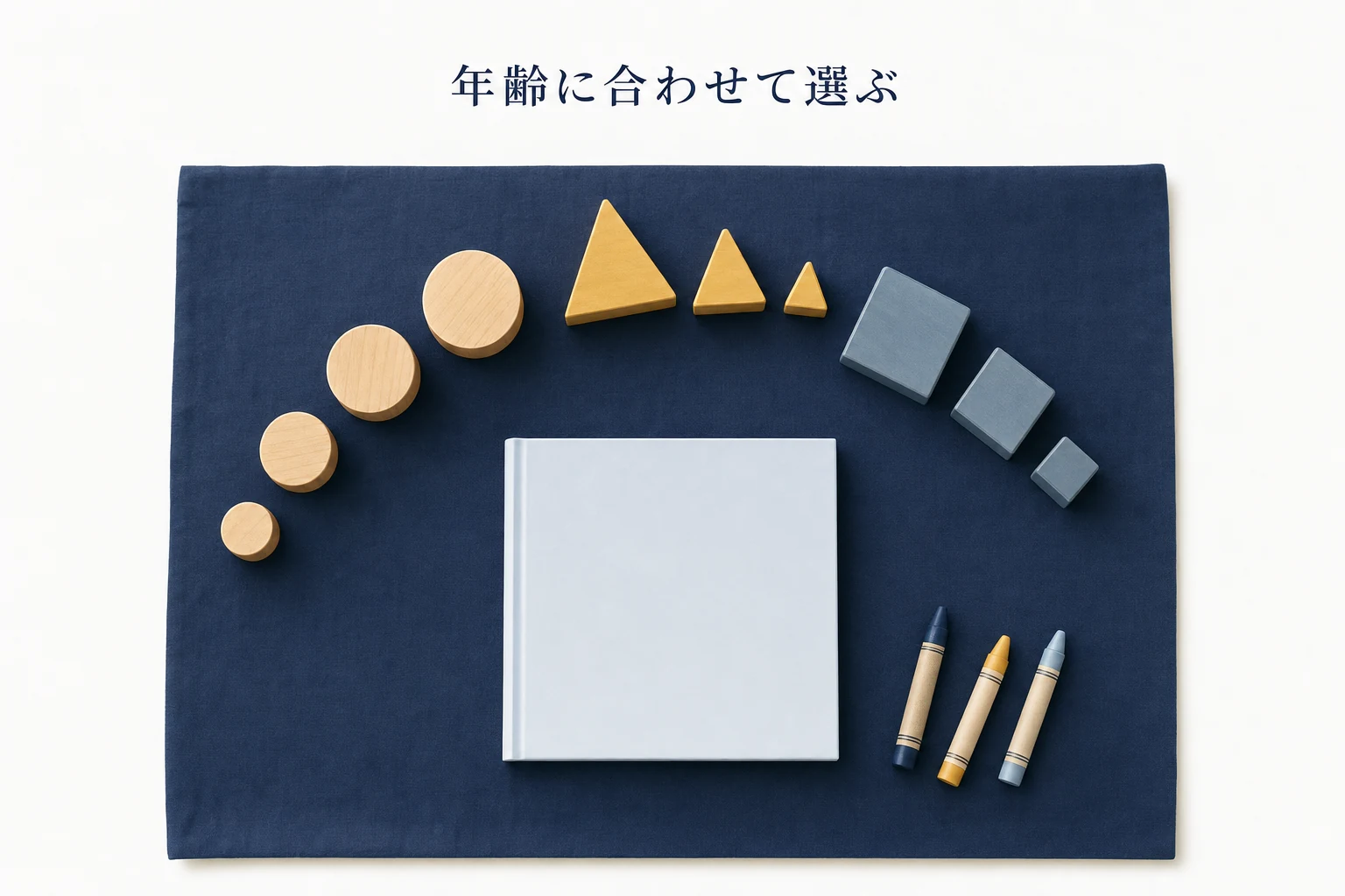 木のおもちゃブロックと無地の絵本、クレヨンを俯瞰で並べた幼児向け通信教育のアイキャッチ